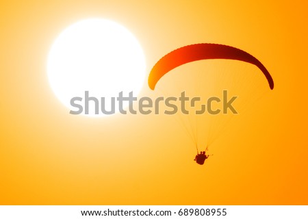Paragliders in tandem fly against the sun and take selfie picture