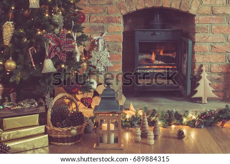 Christmas scene, fireplace with woodburner, lit up Christmas tree with baubles and ornaments, lantern, stars and garlands, selective focus, toned