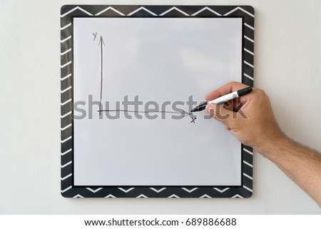 The guy is drawing a schedule on a white board. Male hand with a marker on a white board background.