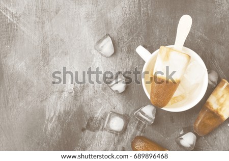 Coffee ice cream popsicles in white cups on a dark background. Top view, copy space. Food background. Toning