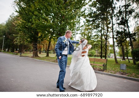 Fabulous young wedding couple posing in the park on the sunny day.