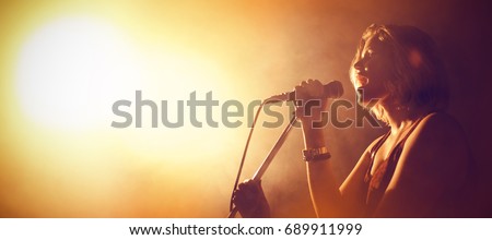 Female singer performing in illuminated club Royalty-Free Stock Photo #689911999