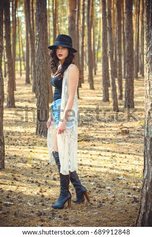 Stylish brunette woman walk  into forest have a grace and charisma. Young lady in fedora black hat and interesting accessorize 