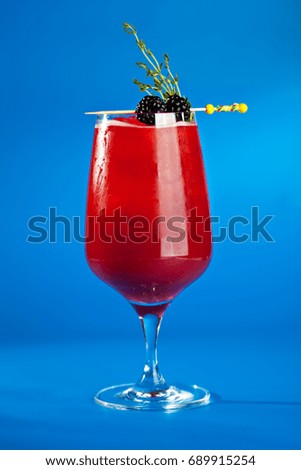 Berry Cocktails for Holiday on Blue Background. Drink Dressed with Blackberry and Thyme