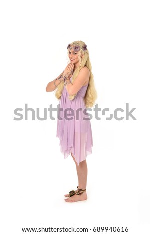 
Full length portrait of a pretty blonde girl  wearing a purple fairy dress. standing pose, isolated against white background.
