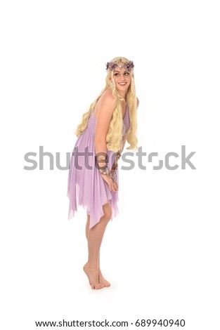 
Full length portrait of a pretty blonde girl  wearing a purple fairy dress. standing pose, isolated against white background.
