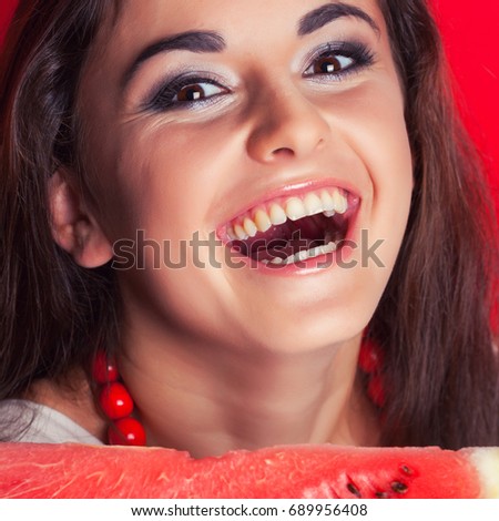 beautiful young woman holding watermelon against red background
