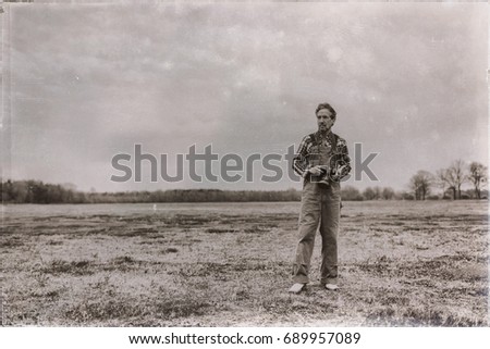 Old sepia photo of nature photographer standing outdoor in grassy area.