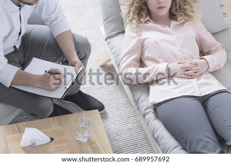 Woman in hypnosis lying on psychotherapist sofa Royalty-Free Stock Photo #689957692