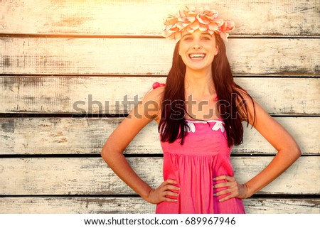 Smiling woman holding wreath of flowers against wood background
