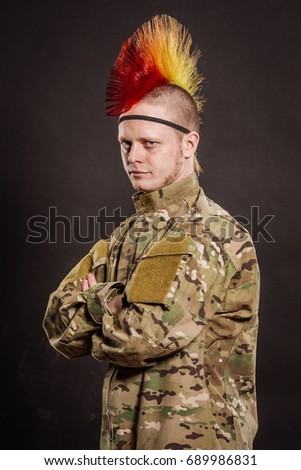Portrait of punk rocker in military camouflage uniform with arms crossed. Military , lifestyle,  people concept