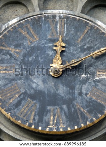 old weathered church tower clock with roman numerals and gold hands stopped at then past twelve with fading paint