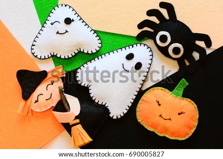 Halloween cute felt ornament decor. Small witch with broom, pumpkin head, two ghosts, spider. Halloween toys crafts on colored felt pieces. Simple kids sewing crafts concept. Top view