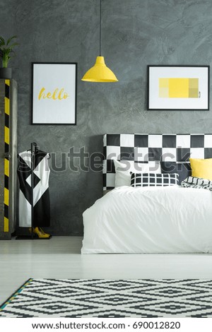 Two pictures above king-size bed in black and white bedroom with yellow elements