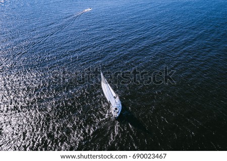 Aerial photography of yacht with white sails in dark blue open space. The good wind fills sails on a sunny summer day. 