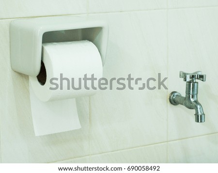 Toilet paper on white wall in toilet room.