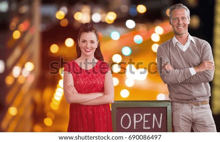 Portrait of coworker with arms crossed standing open sign against glowing road in city at night