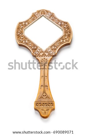 Antique hand mirror in a wooden carved frame lies on a white background