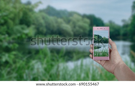 Tourist taking a picture of wild lake using a smartphone, point of view shot