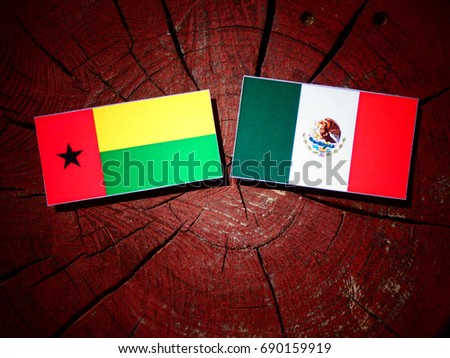 Guinea Bissau flag with Mexican flag on a tree stump isolated