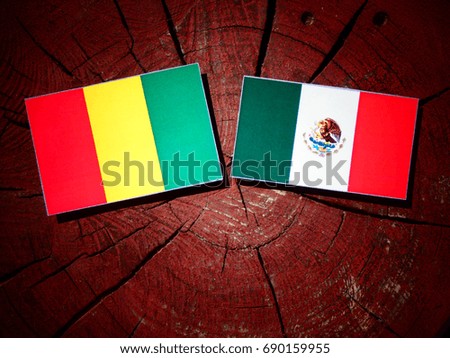 Guinean flag with Mexican flag on a tree stump isolated