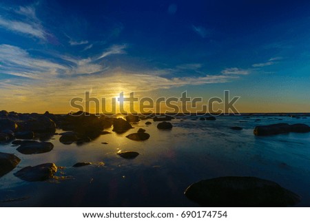 Sunset over the sea, stones at foreground
