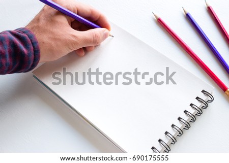 The left-hander writes in a notebook mockup Royalty-Free Stock Photo #690175555
