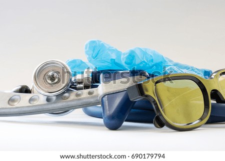 Set of medical doctor's diagnostic tools - stethoscope or phonendoscope, close to medical gloves and glasses lying on table in medical clinic on white -gray background. Preparation tools for diagnosis