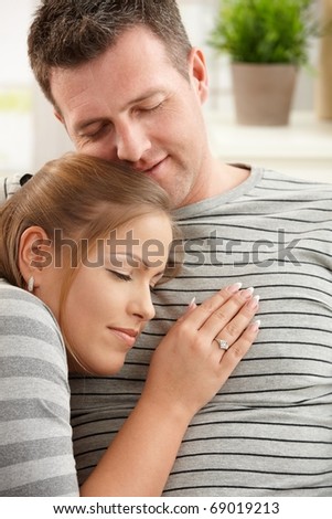 Content couple sitting on sofa together, smiling with eyes closed.?