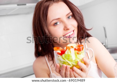 beautiful young woman eating salad in the kitchen  at home