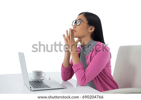 Thoughtful female executive with laptop against white background