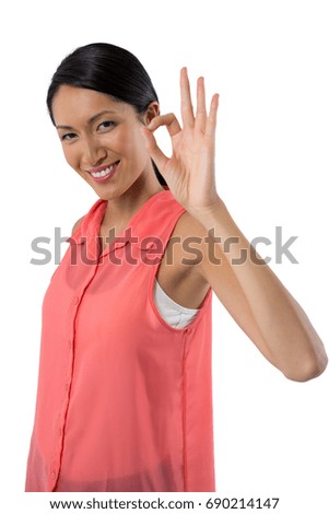 Portrait of smiling woman gesturing okay hand sign against white background