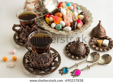 Traditional Turkish Tea on white surface with colorful candies.Conceptual image