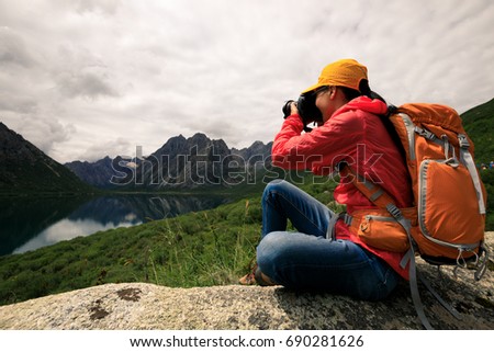 young  woman photographer taking photo in mountains