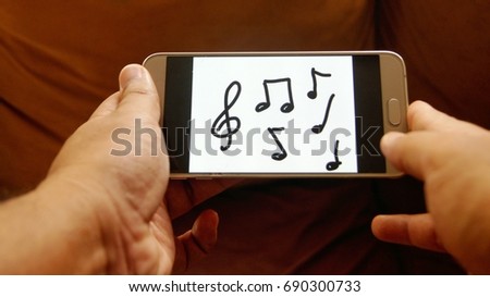 Hand holding smart phone with music note icon on phone screen