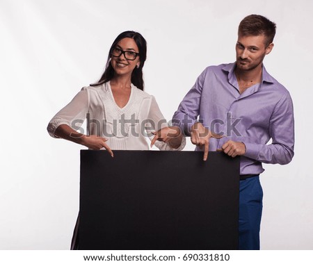 Young confident woman portrait of a confident businesswoman showing presentation, pointing placard gray background. Ideal for banners, registration forms, presentation, landings, presenting concept.