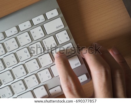 Right index finger hit the enter button on Thai-English language wireless keyboard