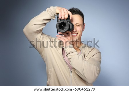 Handsome photographer with camera on light background