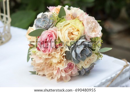 Wedding bouquet with english roses and succulents on table. Natural light, selective focus. 