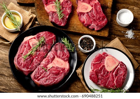 Raw beef meat cross cut for ossobuco cut on a board over rustic wooden background