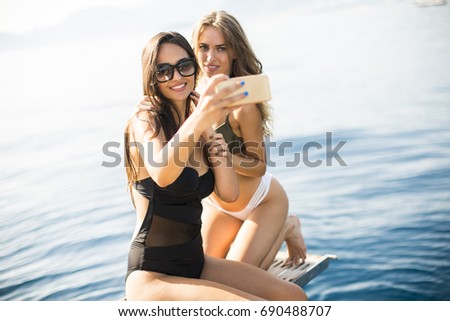 Two pretty young women taking selfie on vacation by the sea