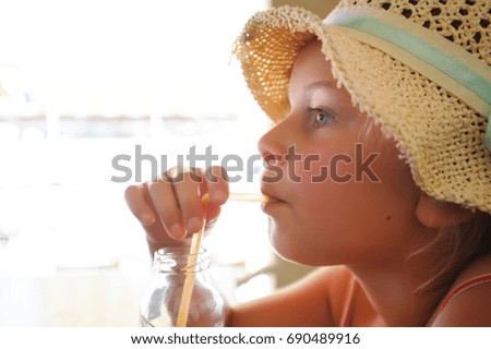 little girl with hat drinking with straw