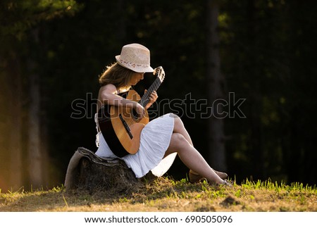 Young girl playing guitar in the nature