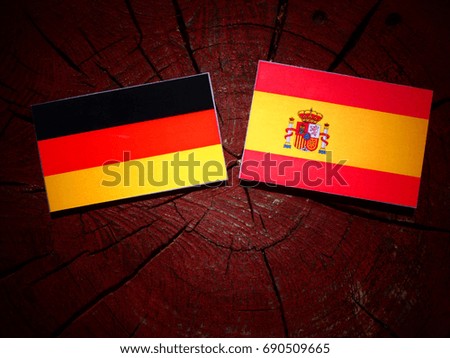 German flag with Spanish flag on a tree stump isolated