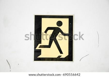 Stickman running through a magical door on a white white wall, discovering a magical world where no stickman has gone before. Also known as an exit sign.