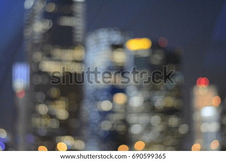 A blurred vision of nightlife high building with the round colorful light on in front of the dark grey shade of sky