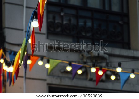 Colorful pennants and lamps hanging in front of a building at a street fair