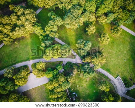 Top view aerial photo from flying drone of a city park with walking path and green zone trees in evening time Royalty-Free Stock Photo #690623500