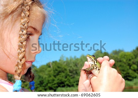 adorable little girl holding a big green frog