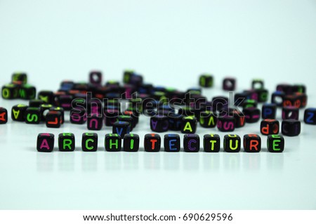 Colorful ARCHITECTURE word printed on small black plastic cubes and placed randomly on white background. 
